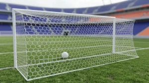 Fußballtor mit weißem Netz am Rand eines grünen Spielfelds